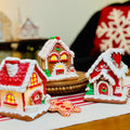 Three gingerbread houses with lit windows on a tablecloth with a blurred background