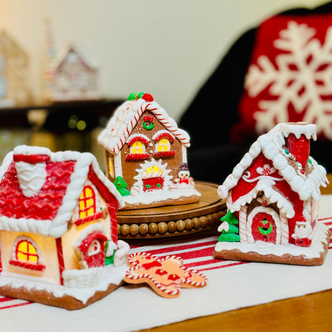 Three gingerbread houses with lit windows on a tablecloth with a blurred background