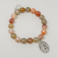 Beaded bracelet with a silver charm on a light gray background
